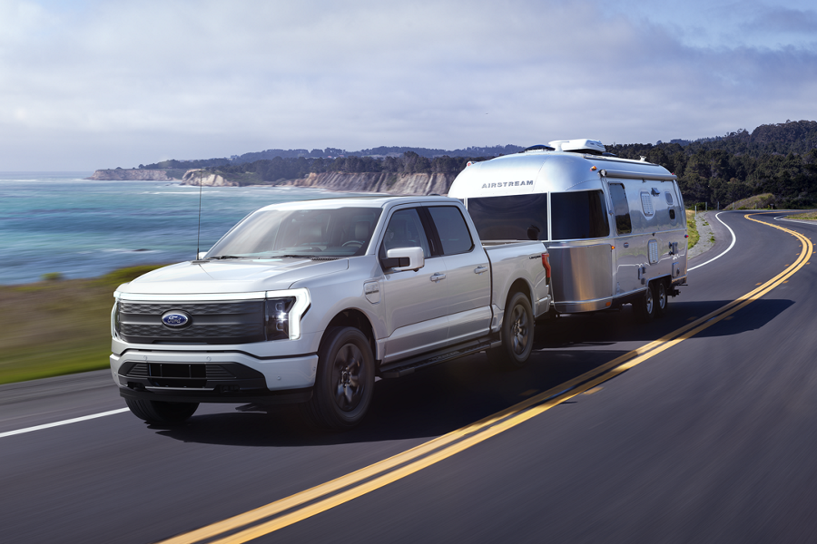 A ford F 1 50 Lightning pulls an Airstream trailler along a 2 lane highway